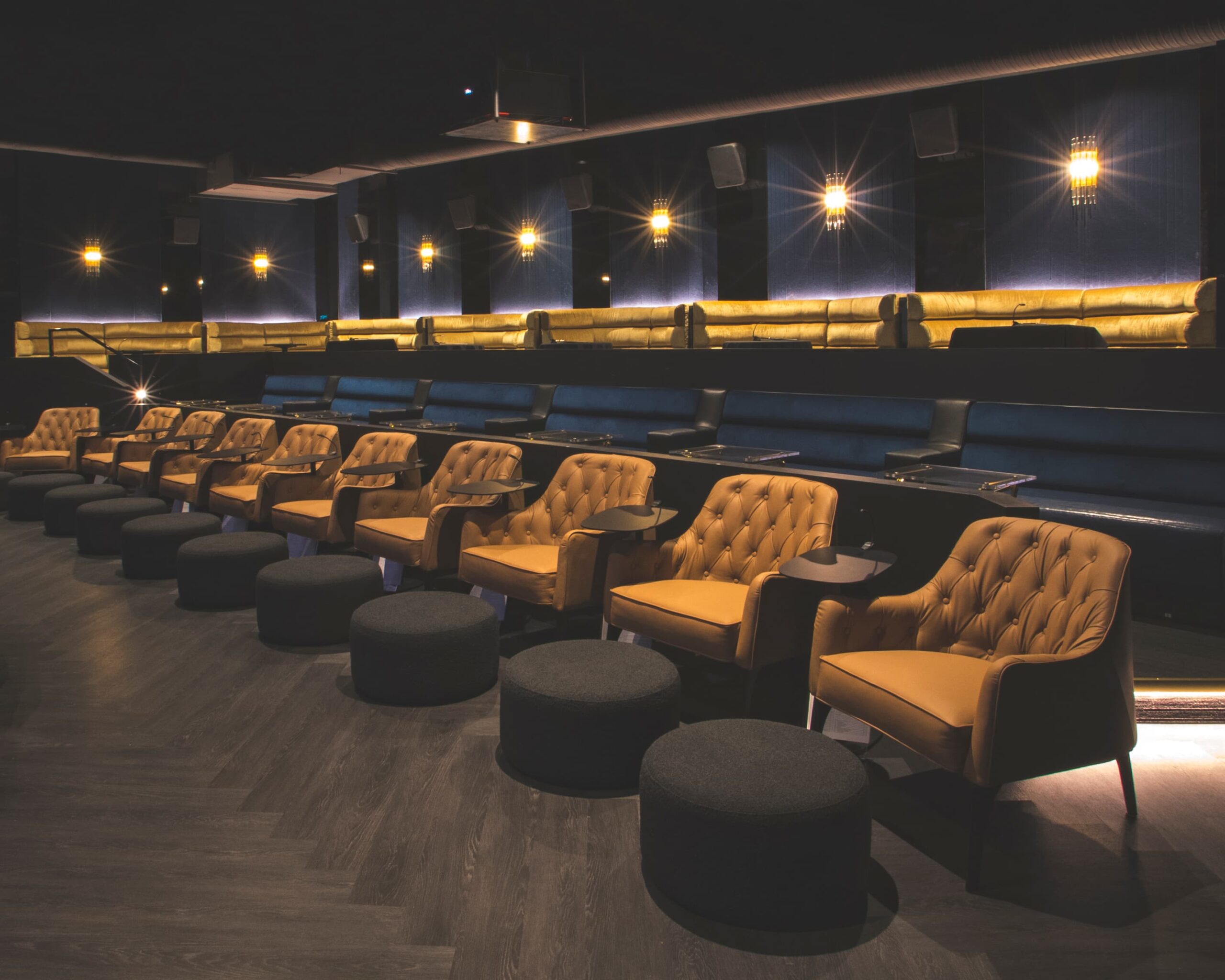 Cinema room with gold chairs in the front row and booths at the back